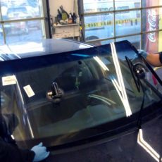 Car in shop with two technicians replacing windshield
